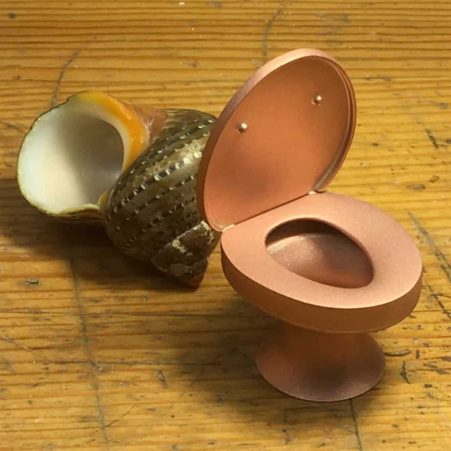 miniature copper toilet next to hermit crab shell